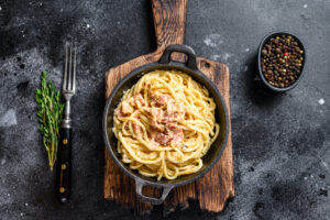 Pasta Carbonara with bacon and parmesan in a pan. Black backgrou